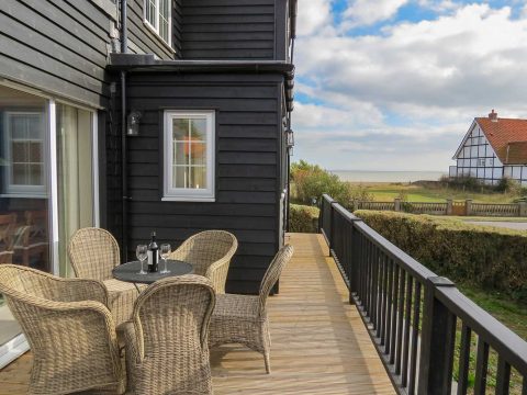 6 The Benthills, family seaside cottage in Thorpeness - decked balcony with wicker chairs and a view to the sea