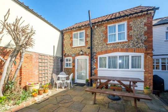 Stable Cottage, Suffolk holiday cottage in Saxmundham - brick and flint exterior with paved courtyard, picnic bench and bistro table