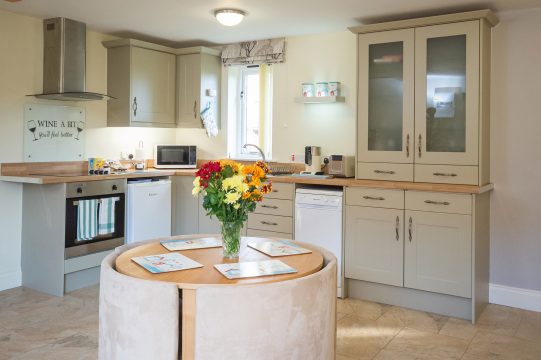 Framlingham Granary Cottage, pet friendly cottage in Benhall - kitchen with sage green units and round dining table
