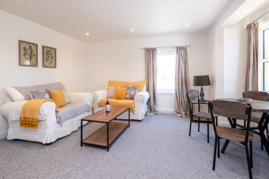 Elm, countryside apartment at Three Tuns, Pettistree - sitting room with white sofas, yellow throws and dining table