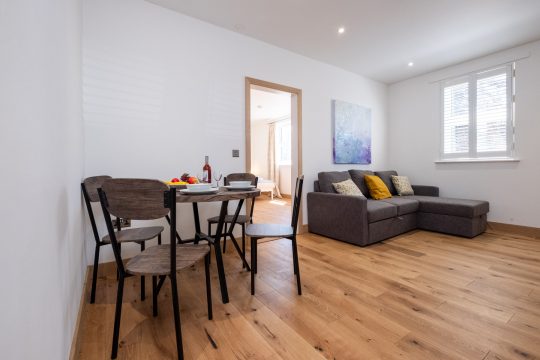 Hazel, countryside apartment at Three Tuns, Pettistree - dining table and grey corner sofa on oak flooring