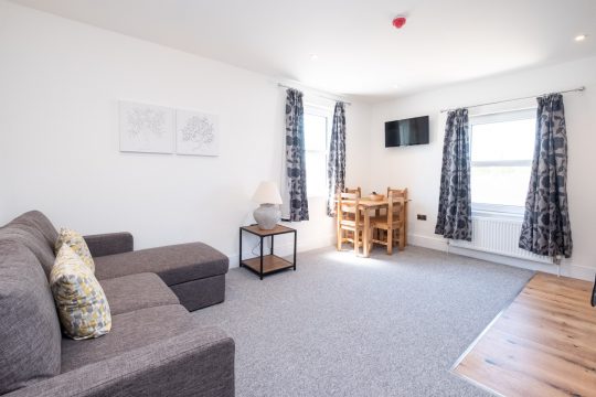 Rowan, two bedroom apartment at Three Tuns, Pettistree - living room with grey corner sofa and dining table by the windows