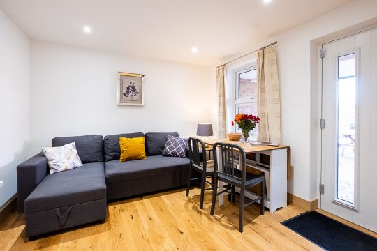 Sycamore, Three Tuns Apartments, Pettistree - living area with corner sofa, dining table and front door