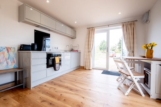 Maple, Three Tuns Apartments, Pettistree - kitchen with grey gloss units and patio doors to the garden