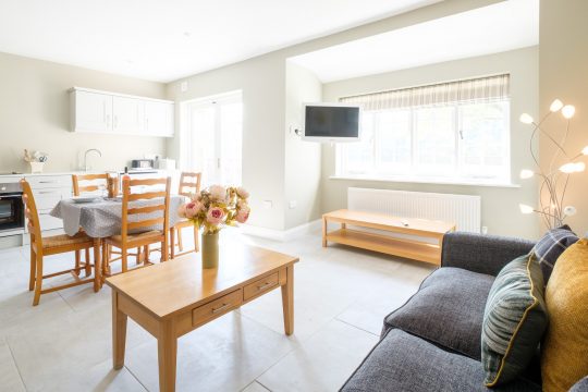 The Dower Cottage, Thorpeness - open plan living room with kitchen, dining table and grey sofa