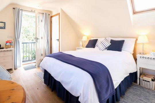 The Bay Tree Studio, studio apartment in Thorpeness - attic bedroom with double bed and doors to a balcony