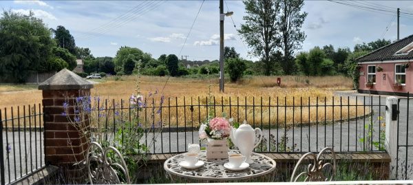 Hazel's, two bedroom cottage in Aldringham - garden table set for tea looking out over the field and village
