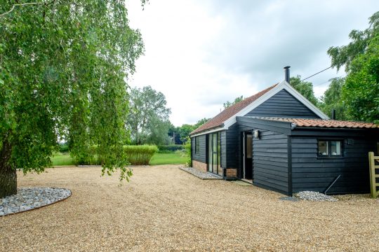 The Half House, detached studio cottage near Snape Maltings - black timber cottage with gravel drive and birch tree