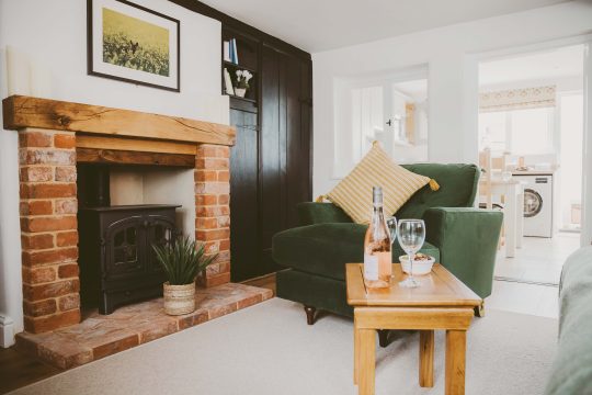 1 Chantry Cottage, two bedroom cottage in Tunstall near Snape - sitting room with brick fireplace, wood burner and green armchair