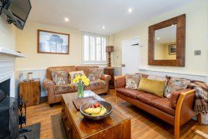 Pebble Cottage, two bedroom fisherman's cottage on Victoria Road, Aldeburgh - sitting room with two leather sofas and open fireplace