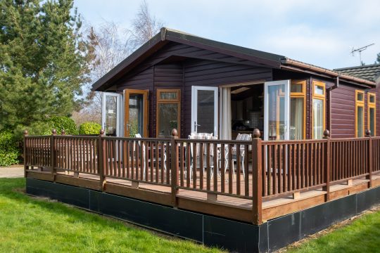 Little Owl, two bedroom cottage in Aldeburgh - timber lodge exterior with decked veranda and open patio doors